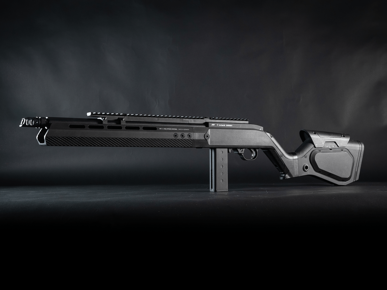 Airsoft-Gewehr in seitlicher Ansicht, modernes Design, schwarzes Finish, auf dunklem Hintergrund.