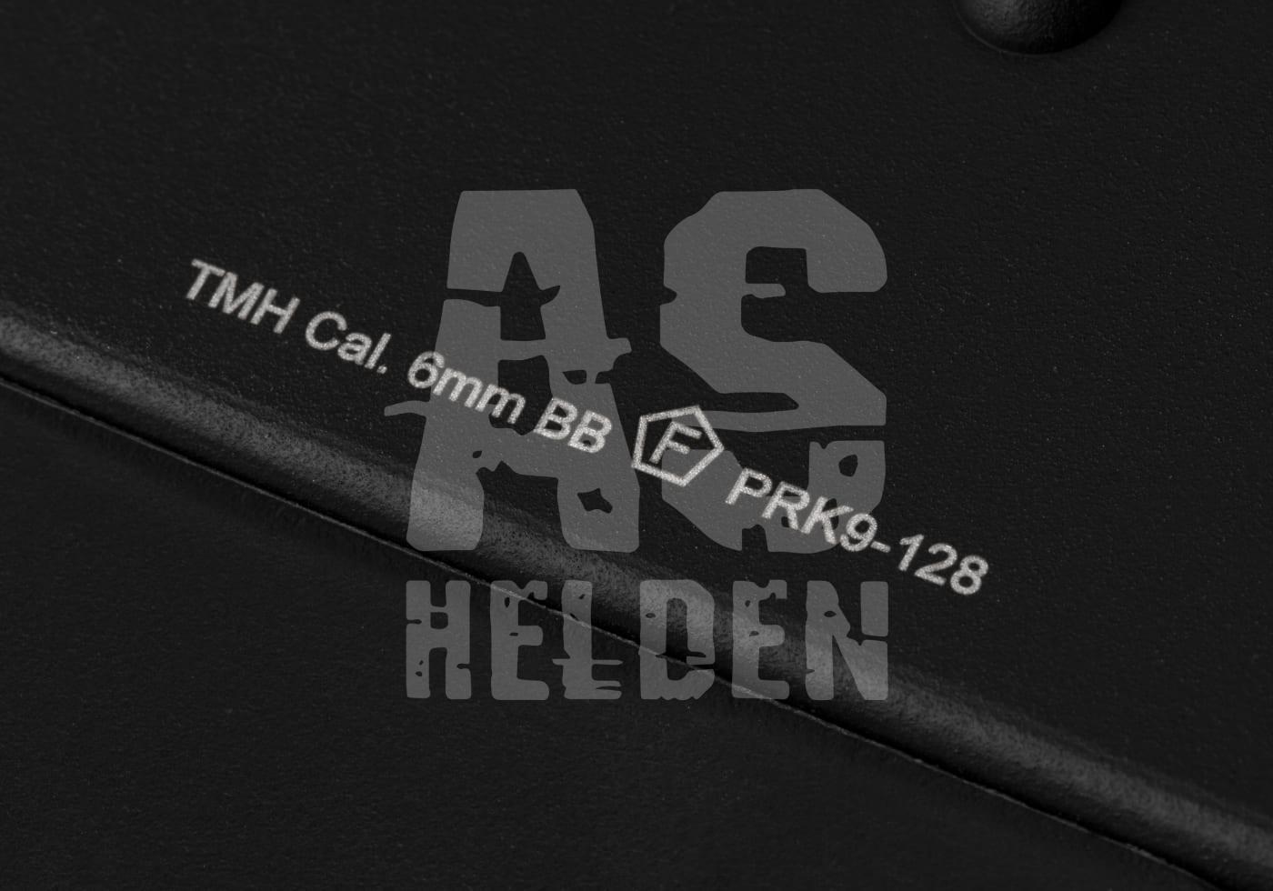 Schwarze Oberfläche mit weißer Gravur: "TMH Cal. 6mm BB" und "PRK9-128". Airsoft-orientiertes Design.